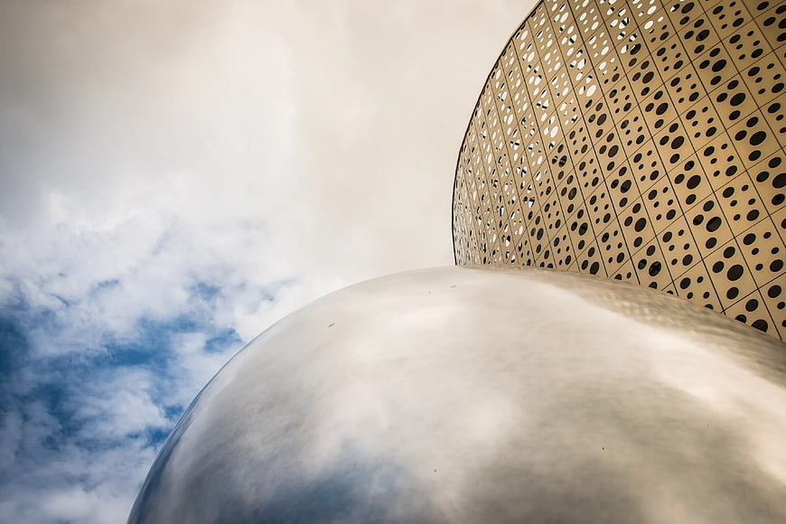 Low angle view of modern perforated architecture against sky