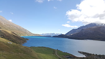 Scenic Alpine Lake Surrounded by Green Hills and Mountains