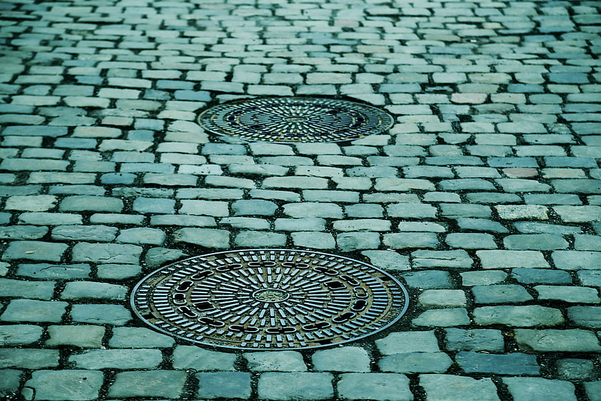 Cobblestone street with two metal manhole covers
