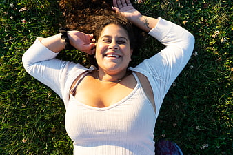 Happy woman lying on grass in white top