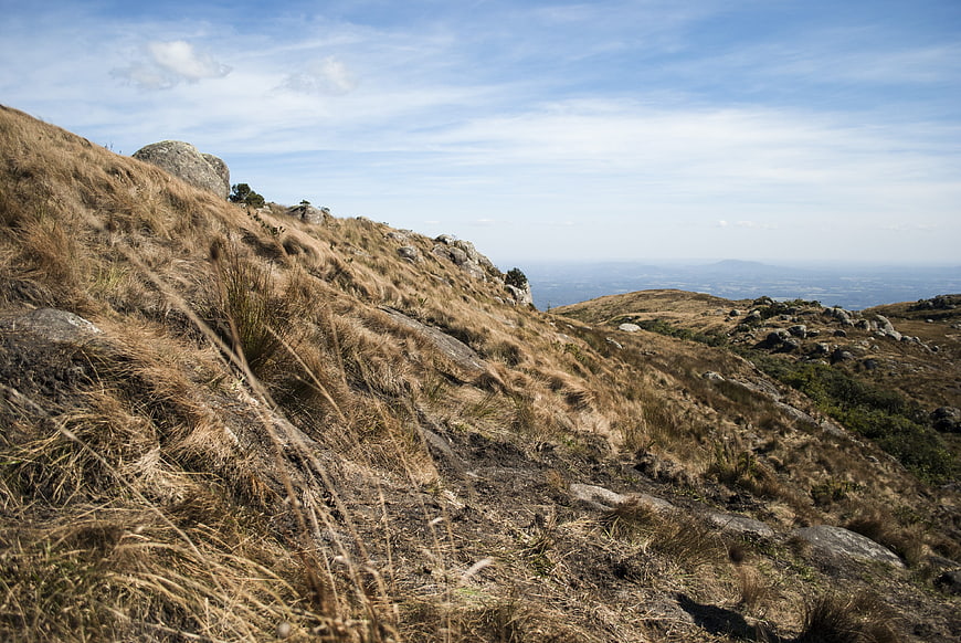 Dry grassy mountain slope with rocky terrain and distant view