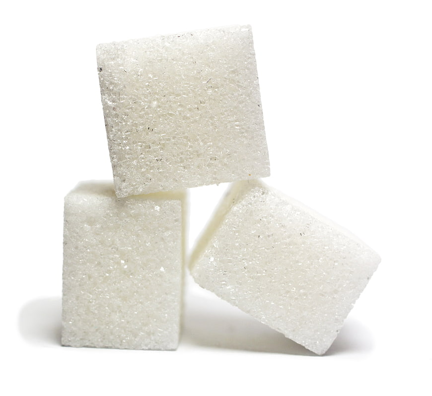 Three white sugar cubes stacked on a clean white background