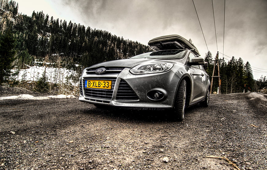 Silver Ford Station Wagon with Roof Box on Gravel Road