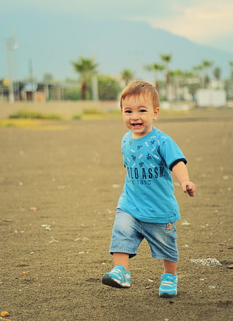 Toddler boy running and smiling on a dirt field outdoors