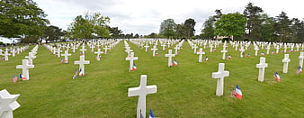 Rows of white crosses in a military cemetery with flags