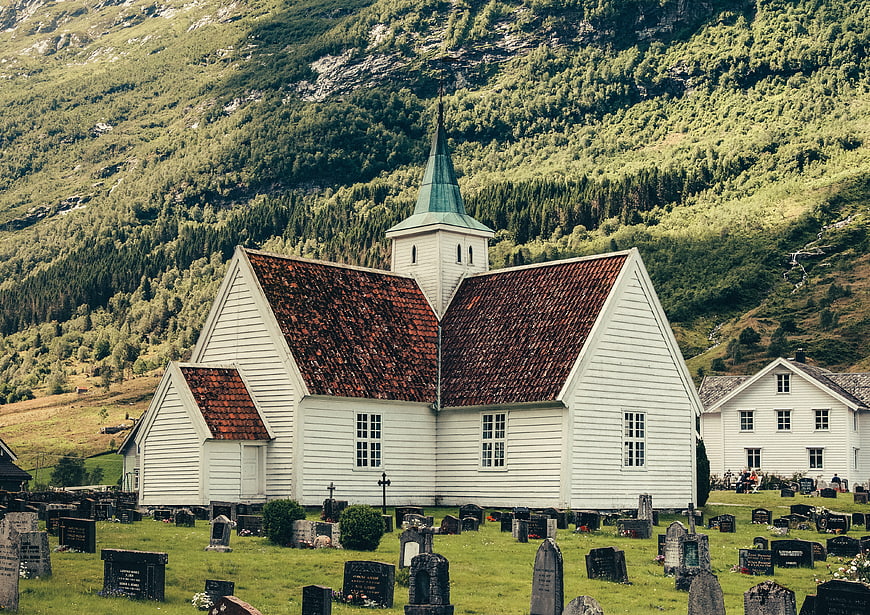 White wooden church with cemetery in green mountain valley