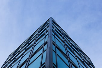 Low angle view of modern glass skyscraper against blue sky