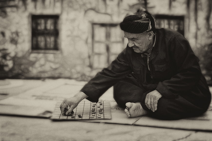 Elderly man playing traditional board game outdoors