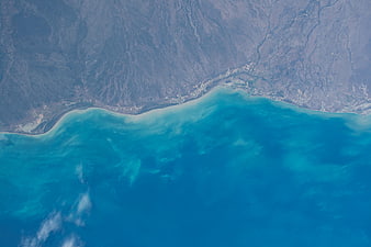 Aerial View of Turquoise Coastline Meeting Arid Mountains