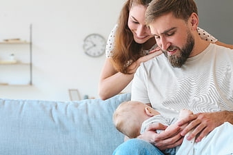 Happy Parents Holding Newborn Baby on Sofa