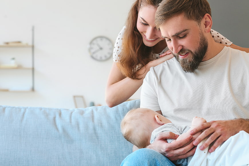 Happy Parents Holding Newborn Baby on Sofa