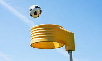 Soccer ball in mid-air above yellow playground hoop