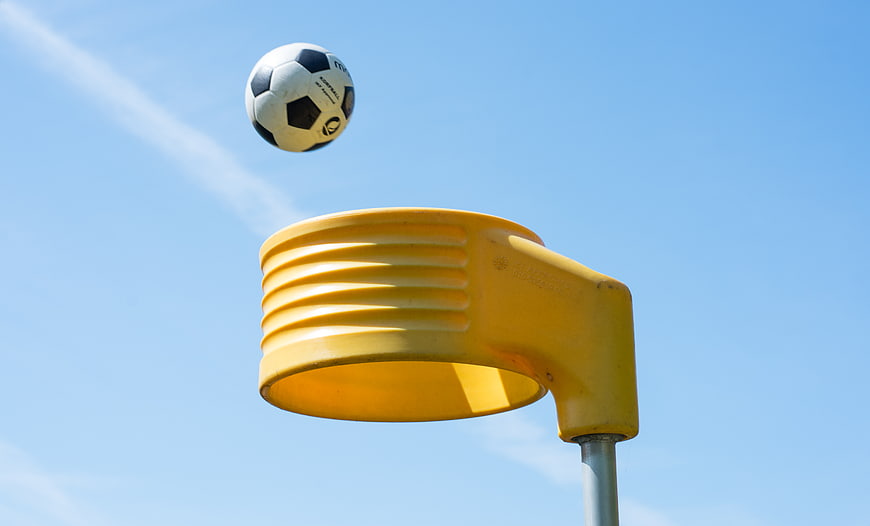 Soccer ball in mid-air above yellow playground hoop