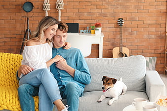 Happy young couple cuddling on sofa with dog