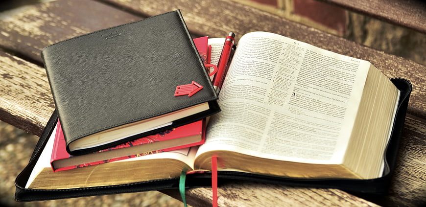 Open Bible with Study Books and Pen on Wooden Bench