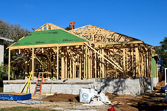 Wooden house frame under construction with blue sky background