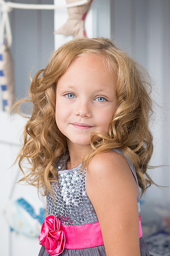 Portrait of a young girl with curly blonde hair and blue eyes