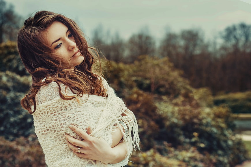 Woman in White Knit Sweater Hugging Herself Outdoors