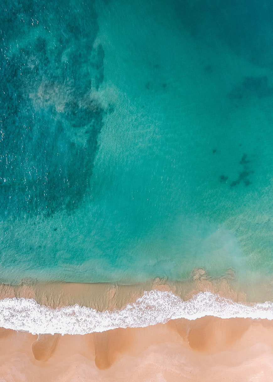 Aerial View of Turquoise Ocean Waves Meeting Sandy Beach