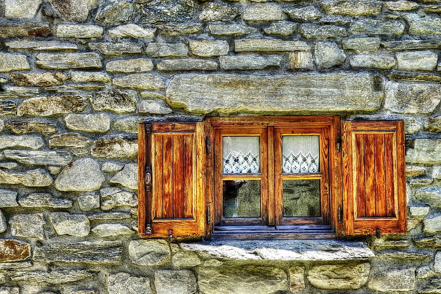 Rustic wooden window with shutters on stone wall
