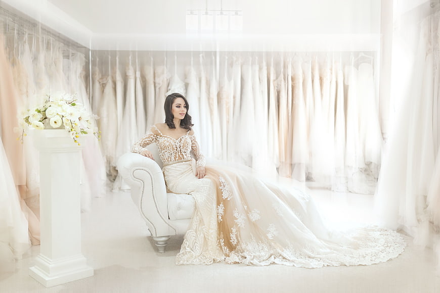 Elegant Bride in Lace Wedding Dress Sitting in Boutique