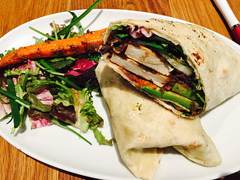 Grilled chicken wrap with avocado and fresh salad on white plate