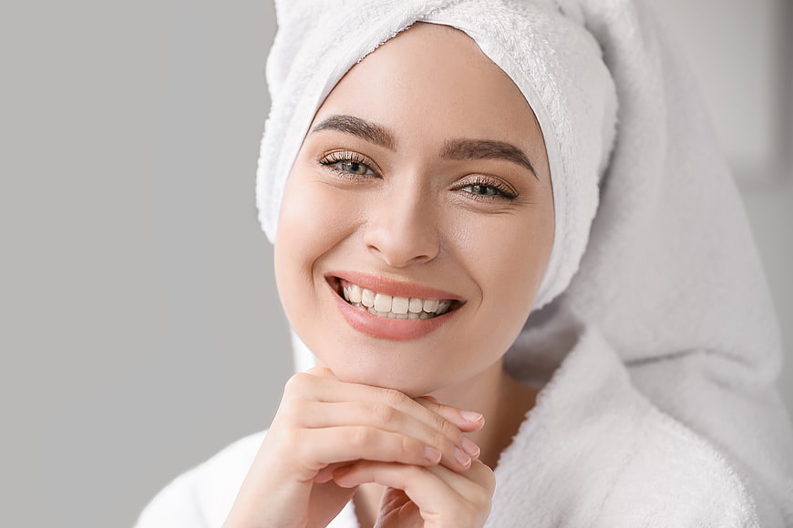 Happy woman with towel on head smiling after spa treatment