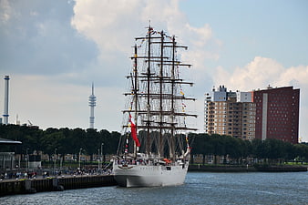 Historic sailing ship docked in Hamburg harbor with skyline