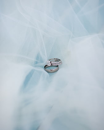 Elegant wedding rings on soft blue tulle fabric background