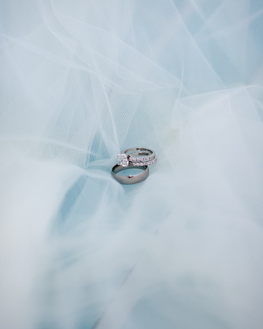 Elegant wedding rings on soft blue tulle fabric background