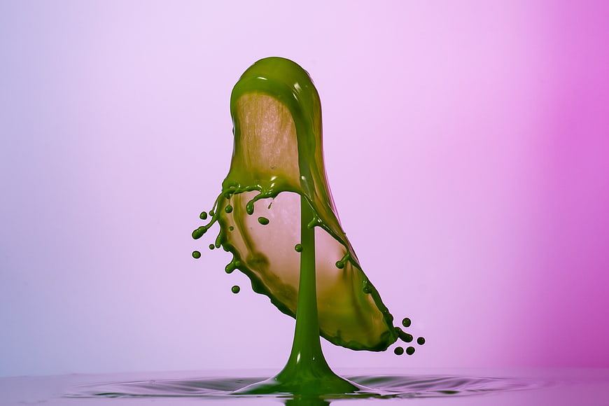Green liquid splash on pink gradient background