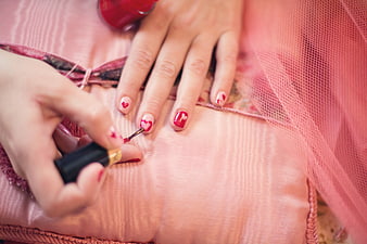 Close-up of woman painting red heart nail art design