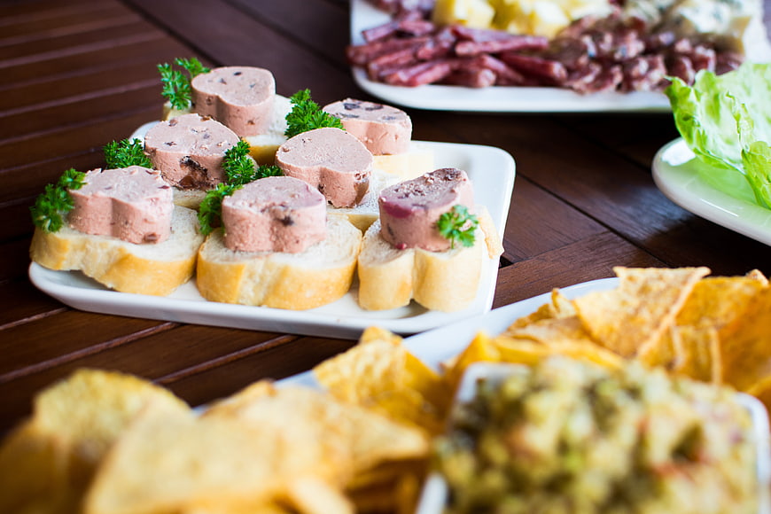 Pate appetizers on baguette slices with chips and salad