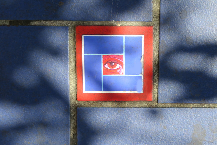 Red eye symbol on blue tiled wall with shadows