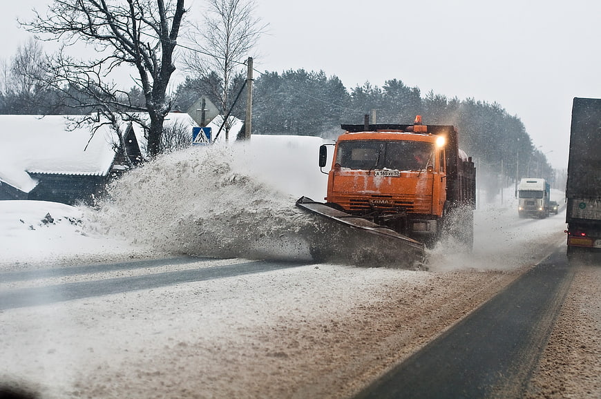 Orange snowplow truck clearing winter road