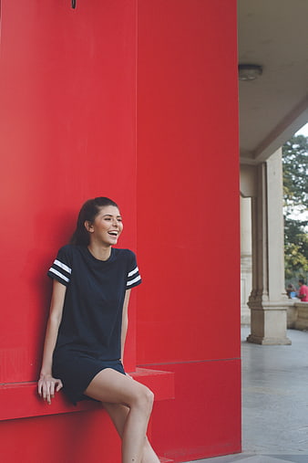 Happy woman laughing against vibrant red wall