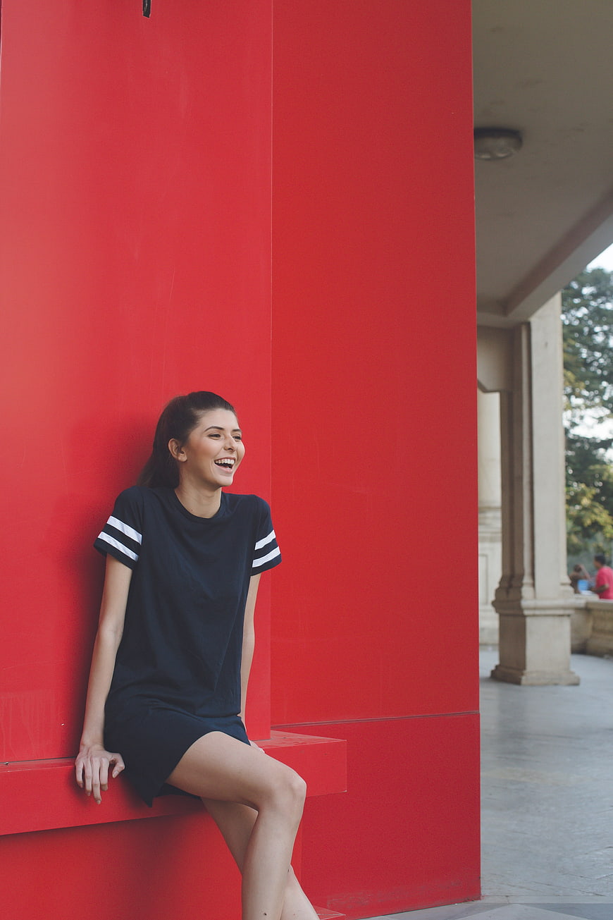 Happy woman laughing against vibrant red wall