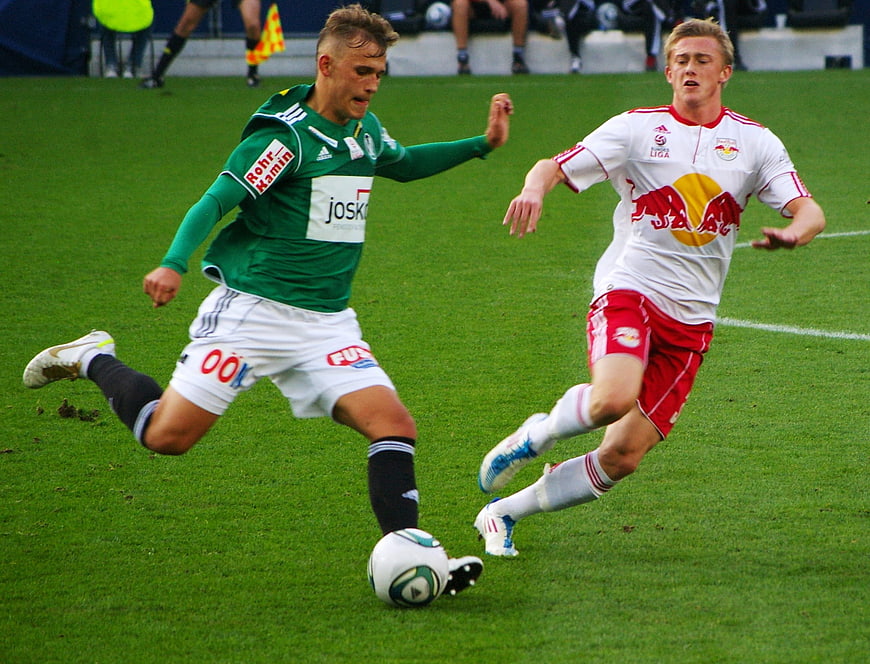 Two soccer players competing for the ball on a green pitch