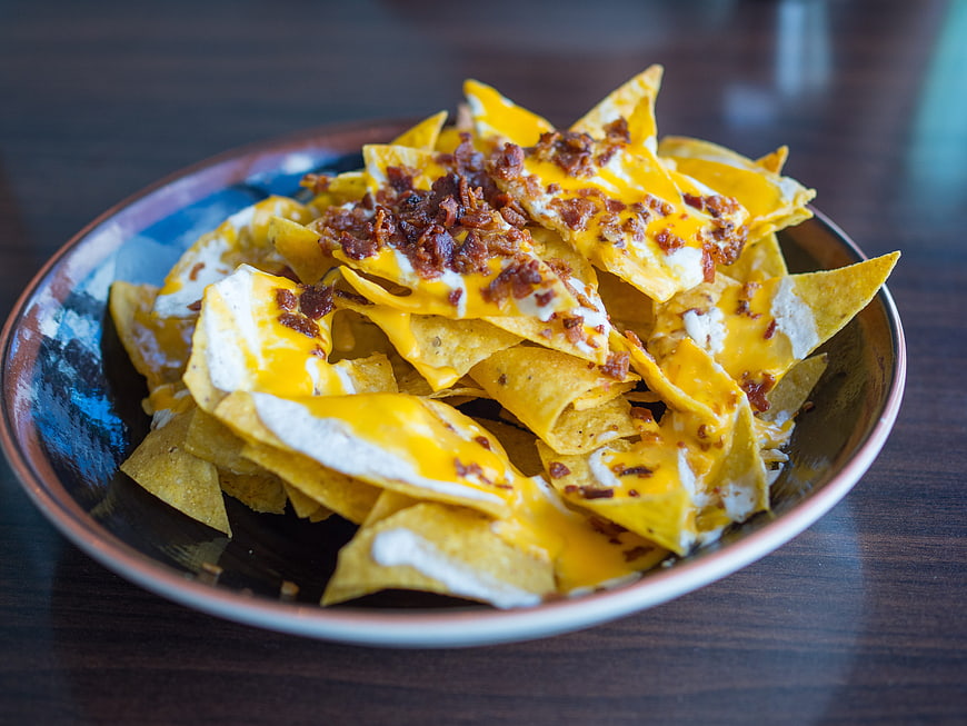 Loaded Nachos With Melted Cheese And Crispy Toppings In Ceramic Bowl