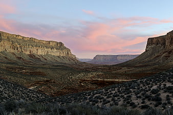 Vast desert canyon landscape with pink sunset sky and rugged cliffs
