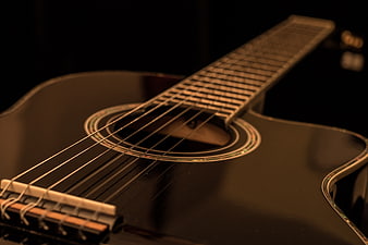 Close-up of black acoustic guitar with warm lighting