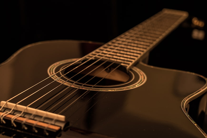 Close-up of black acoustic guitar with warm lighting