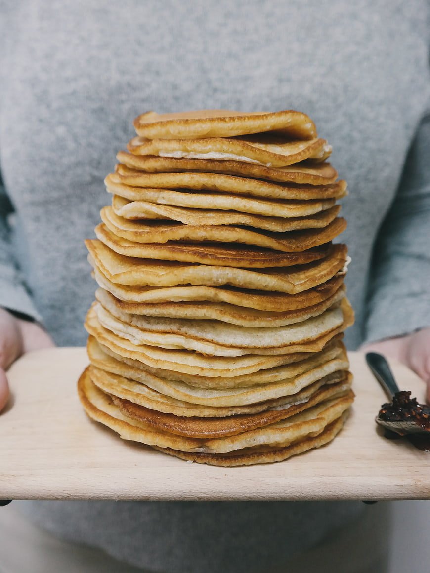 Tall Stack of Golden Pancakes on Wooden Board