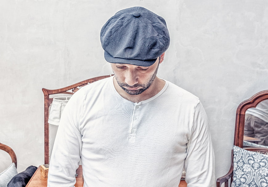 Man in White Henley Shirt and Blue Newsboy Cap Looking Down
