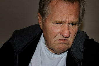 Close-up portrait of an older man with a disgusted and uncomfortable expression
