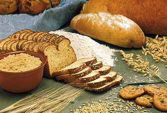 Assortment of fresh bread, flour, wheat, and cookies on table