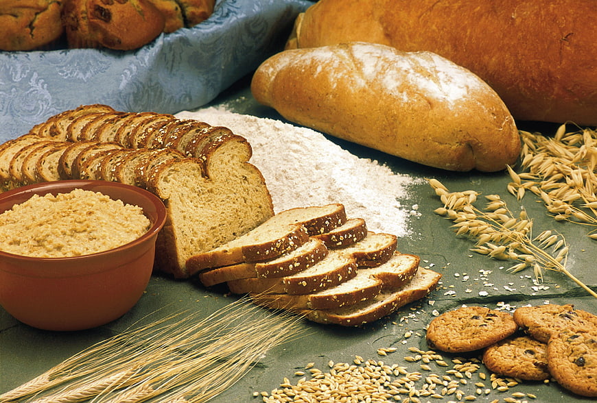 Assortment of fresh bread, flour, wheat, and cookies on table