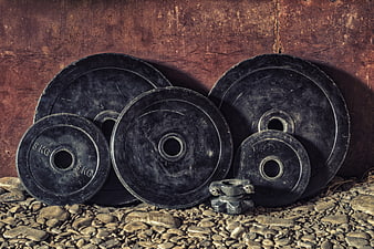 Vintage Black Weightlifting Plates on Gravel Background