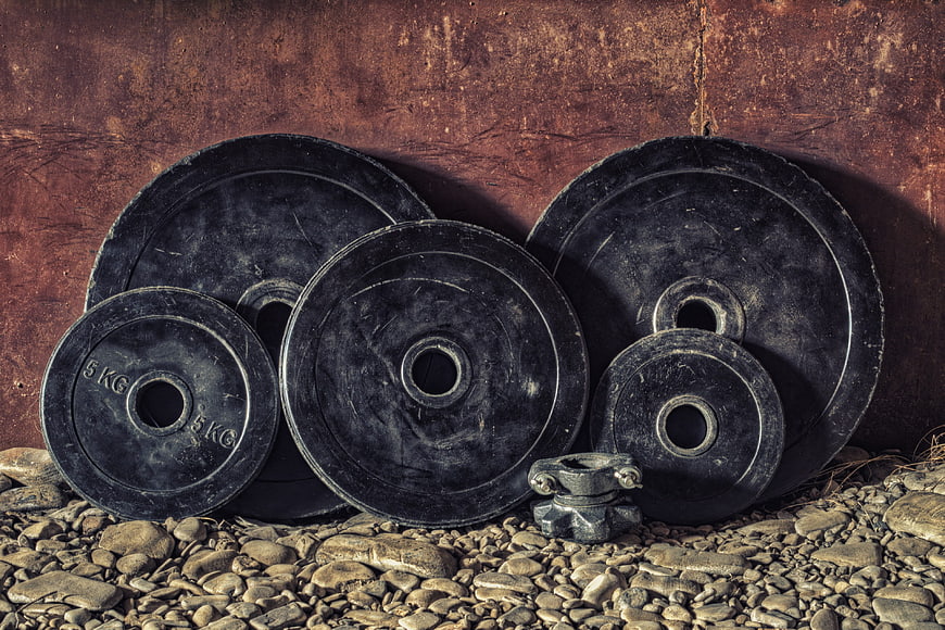 Vintage Black Weightlifting Plates on Gravel Background