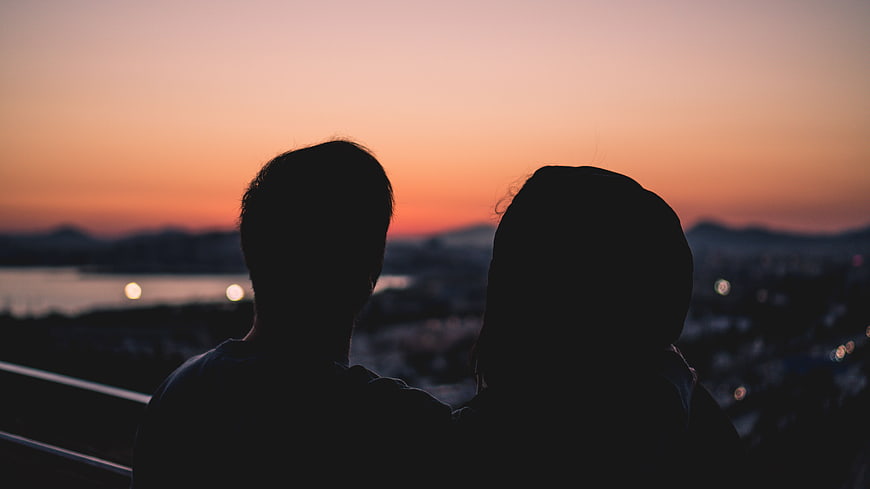 Silhouette of couple watching sunset over city